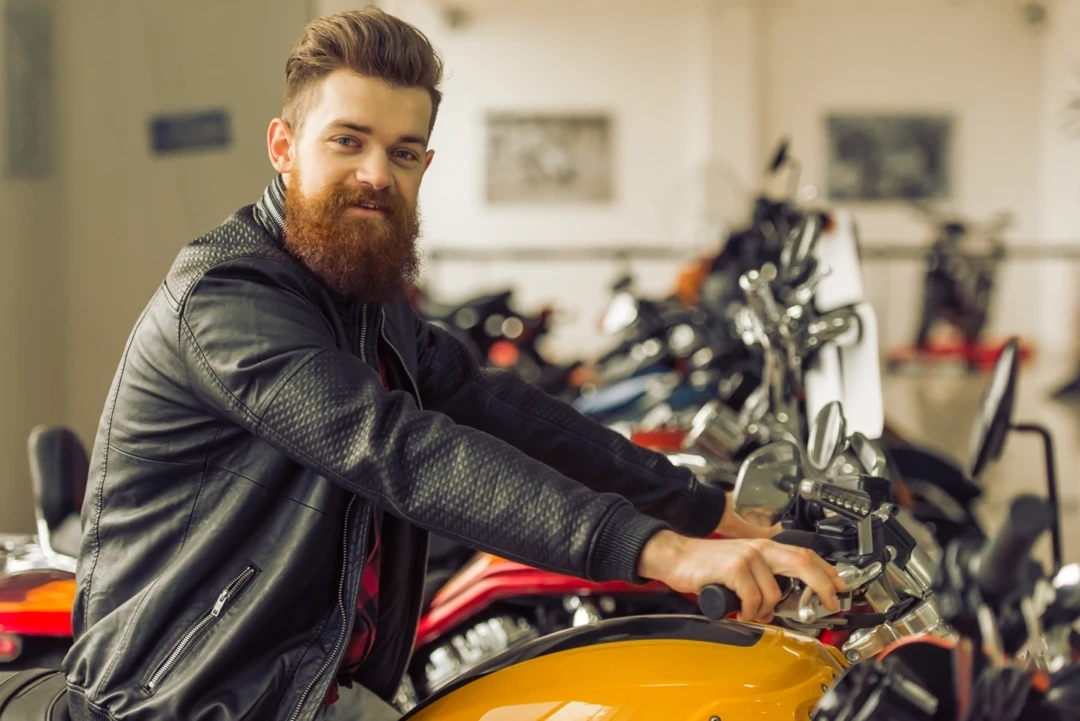 Customer sitting on a motorcycle inside a showroom, illustrating professional motorcycle storage service in Sherbrooke.