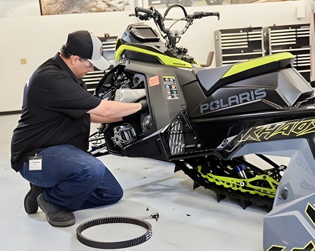 Technician performing maintenance on a Polaris snowmobile in a Sherbrooke workshop to prepare it for winter.