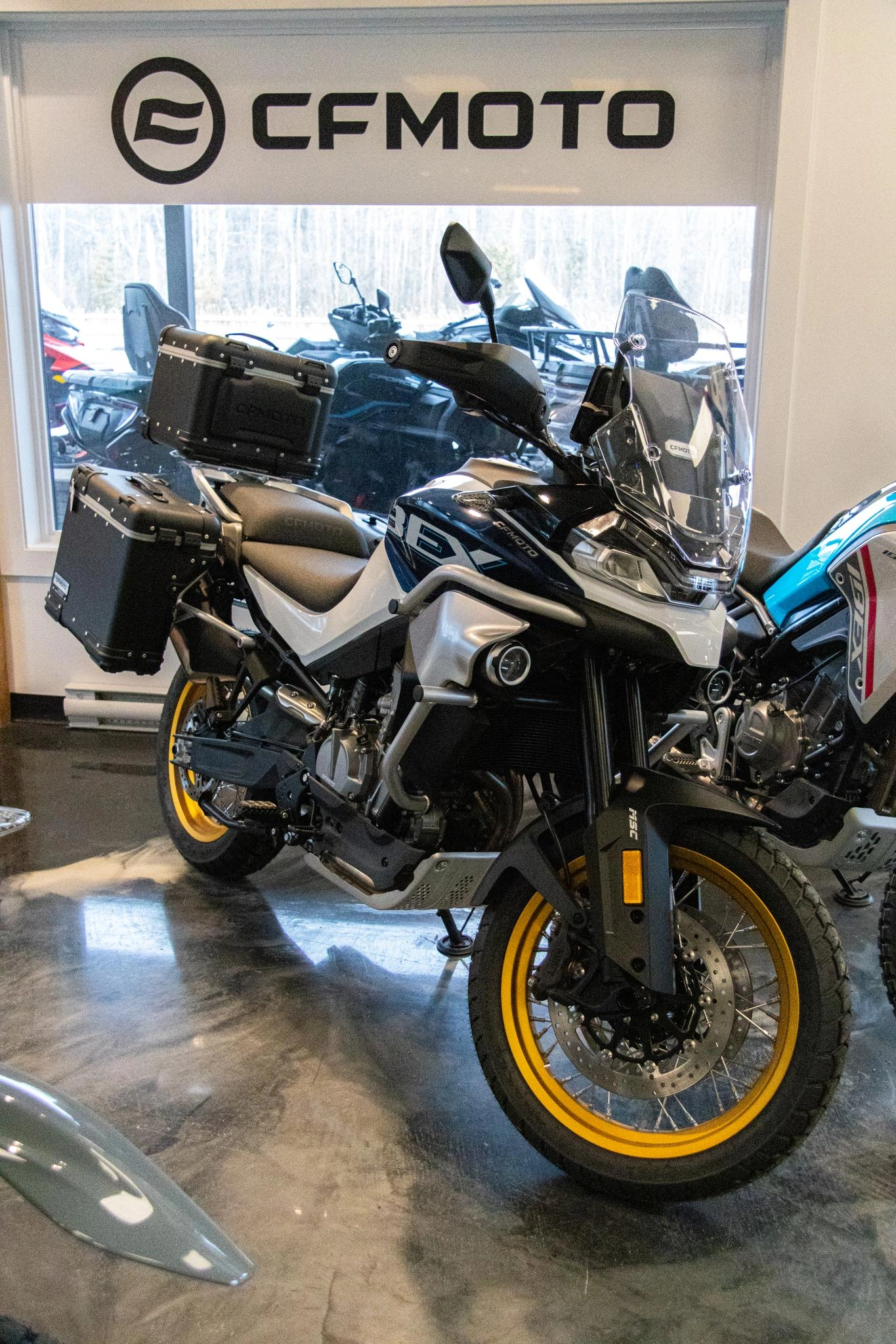 Moto CFMOTO IBEX 800 aventure avec valises latérales et top case en salle de montre, idéale pour voyage et longue distance