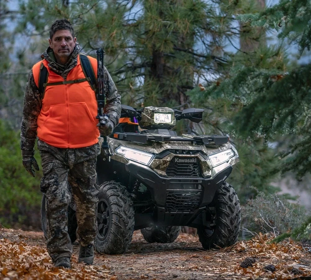 Chasseur avec un Kawasaki Brute Force camouflage en forêt.