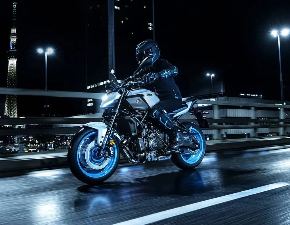 Motocycliste sur une Yamaha MT-07 bleue dans un décor urbain de nuit.