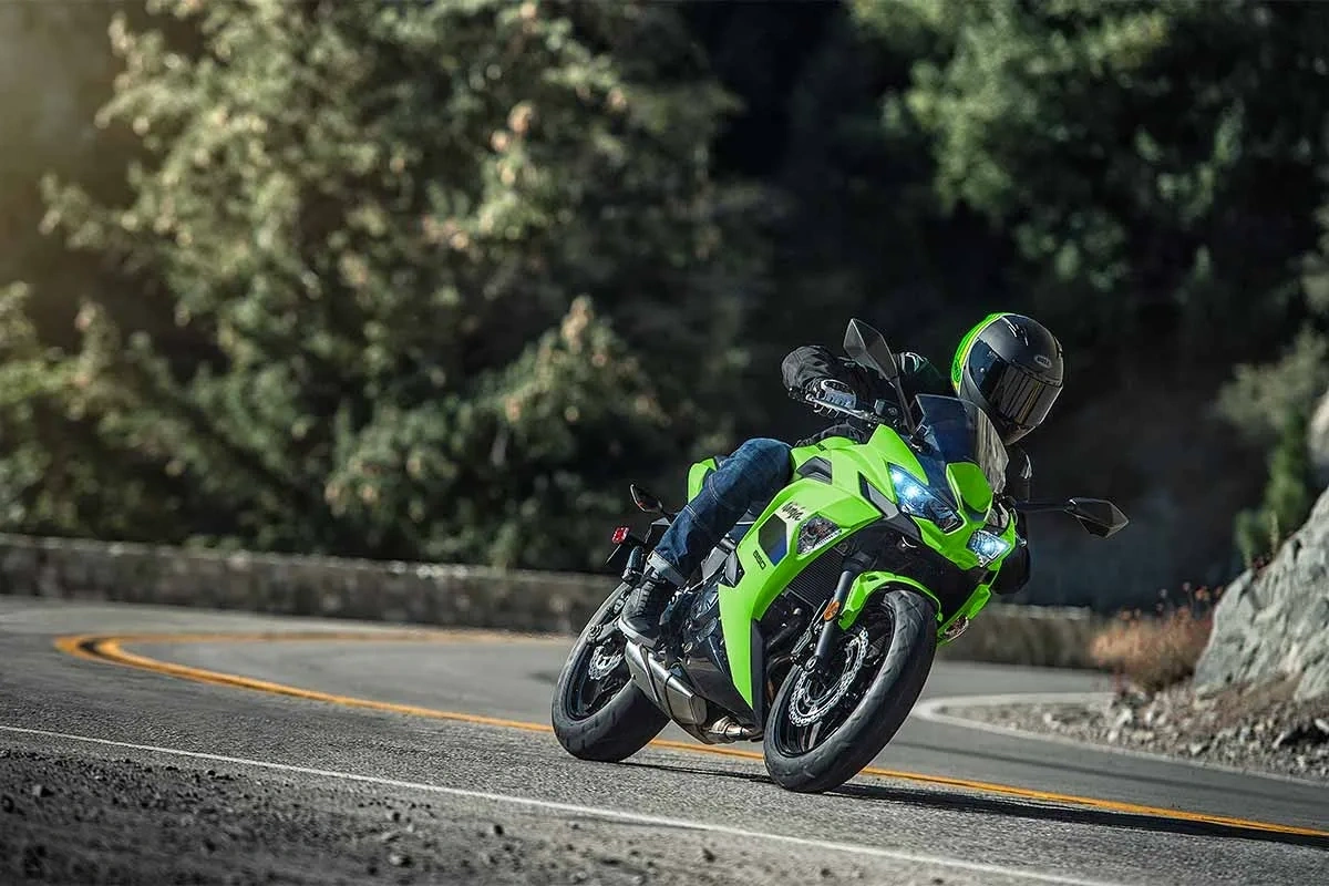 Kawasaki Ninja 650cc 2026 verte en virage sur une route boisée.