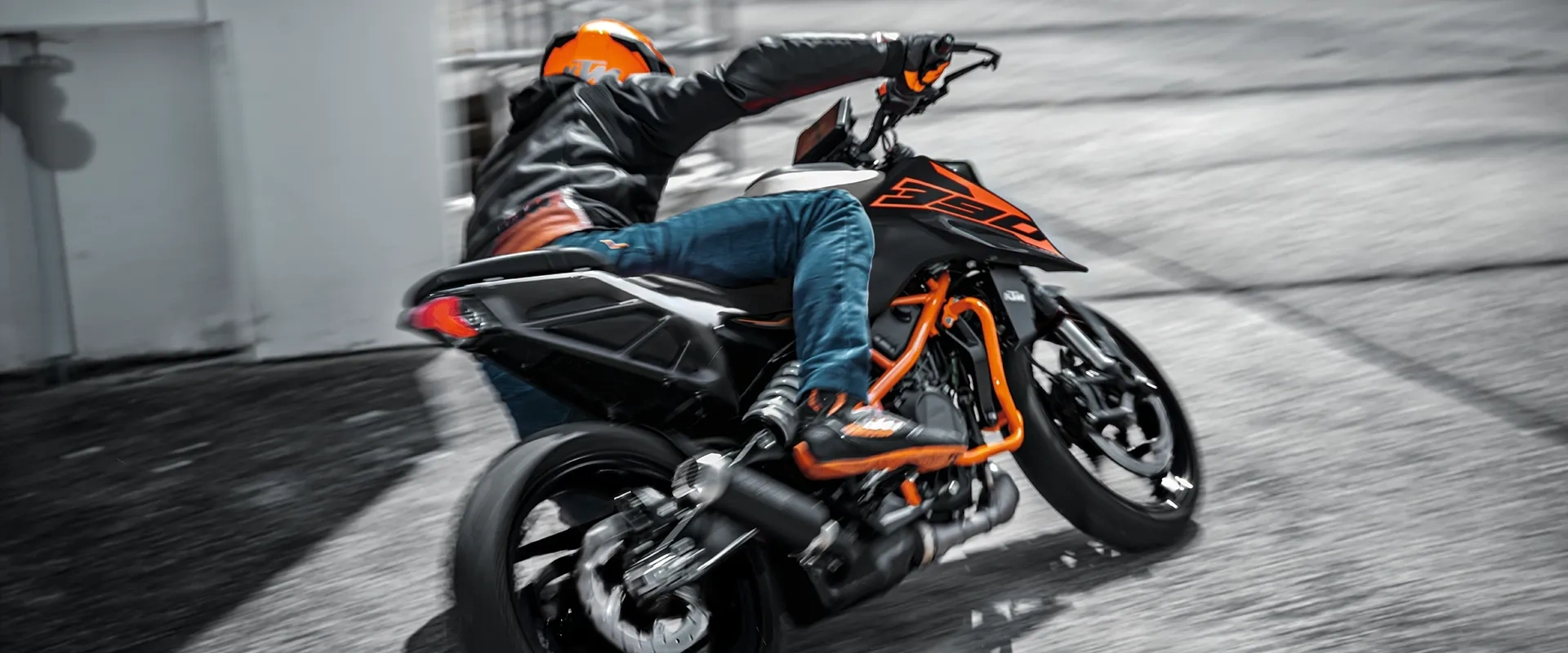 Motocycliste en KTM Duke 390 noire et orange dans un virage urbain.