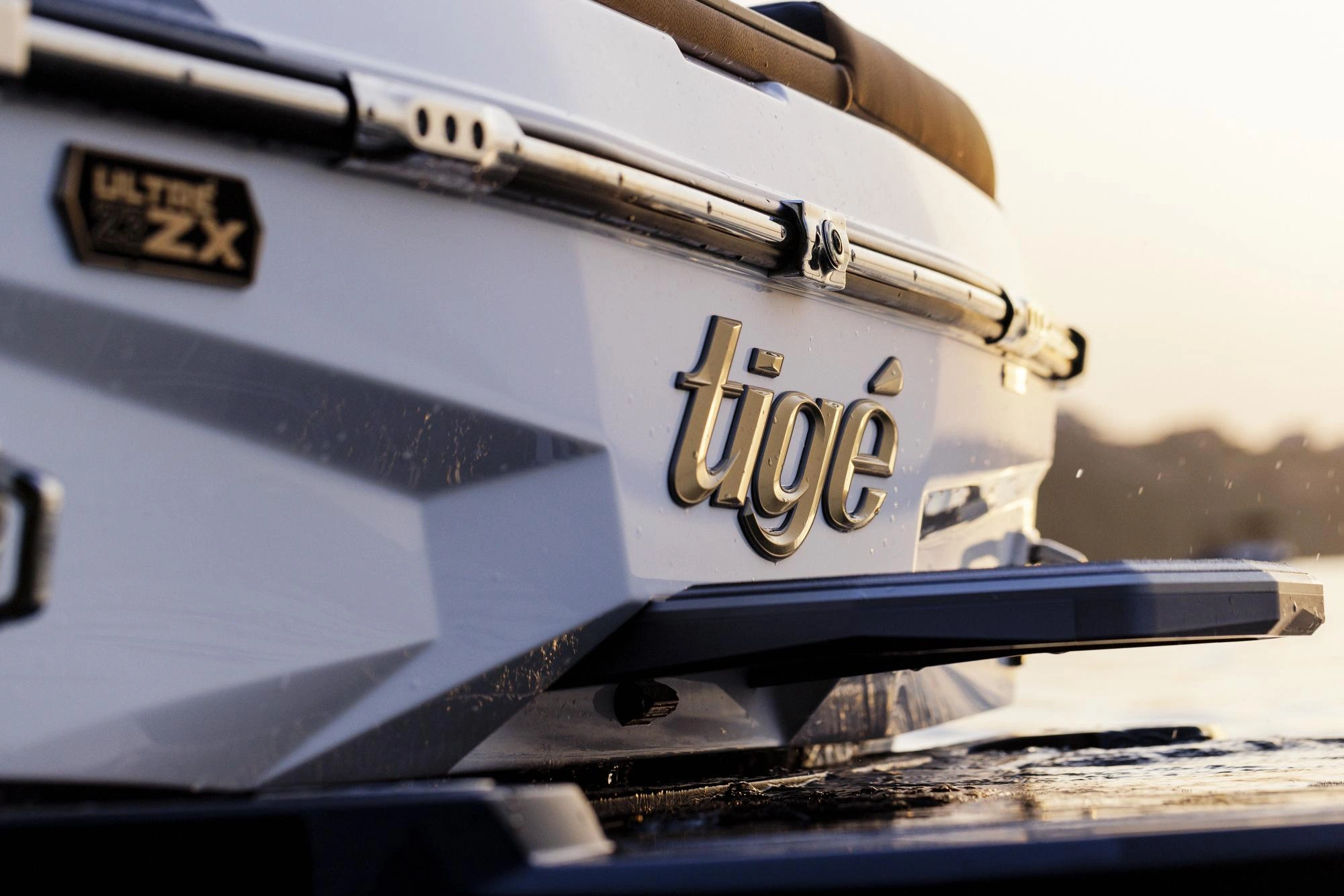 Wake surfer riding a sculpted wave behind a Tige boat on an Alberta lake at golden hour