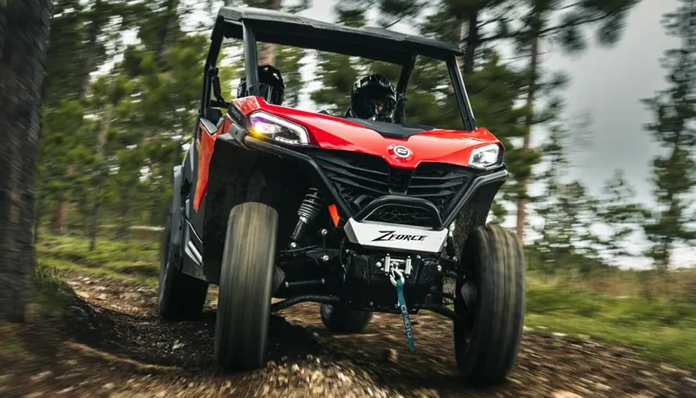 CFMoto ZForce 800 Trail 2026 rouge dévalant un sentier forestier, vue de face en action.
