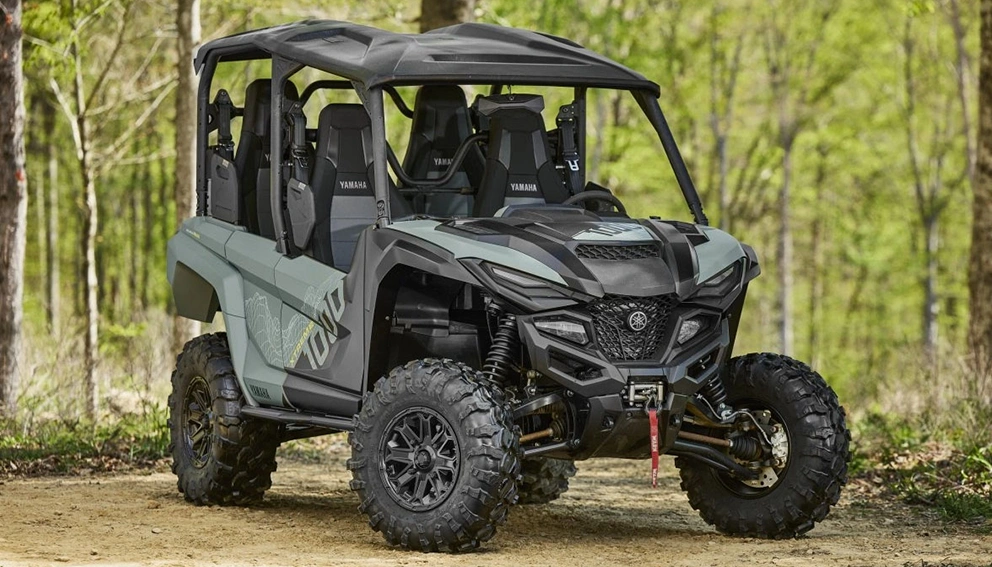 Yamaha Wolverine (côte-à-côte) vert-gris garé sur un chemin de terre en forêt.
