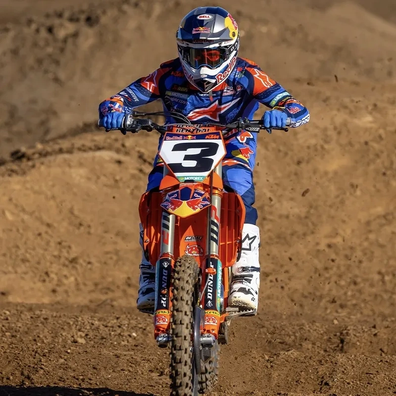 KTM 450 SX-F orange sautant au-dessus d'une bosse sur un circuit de motocross.