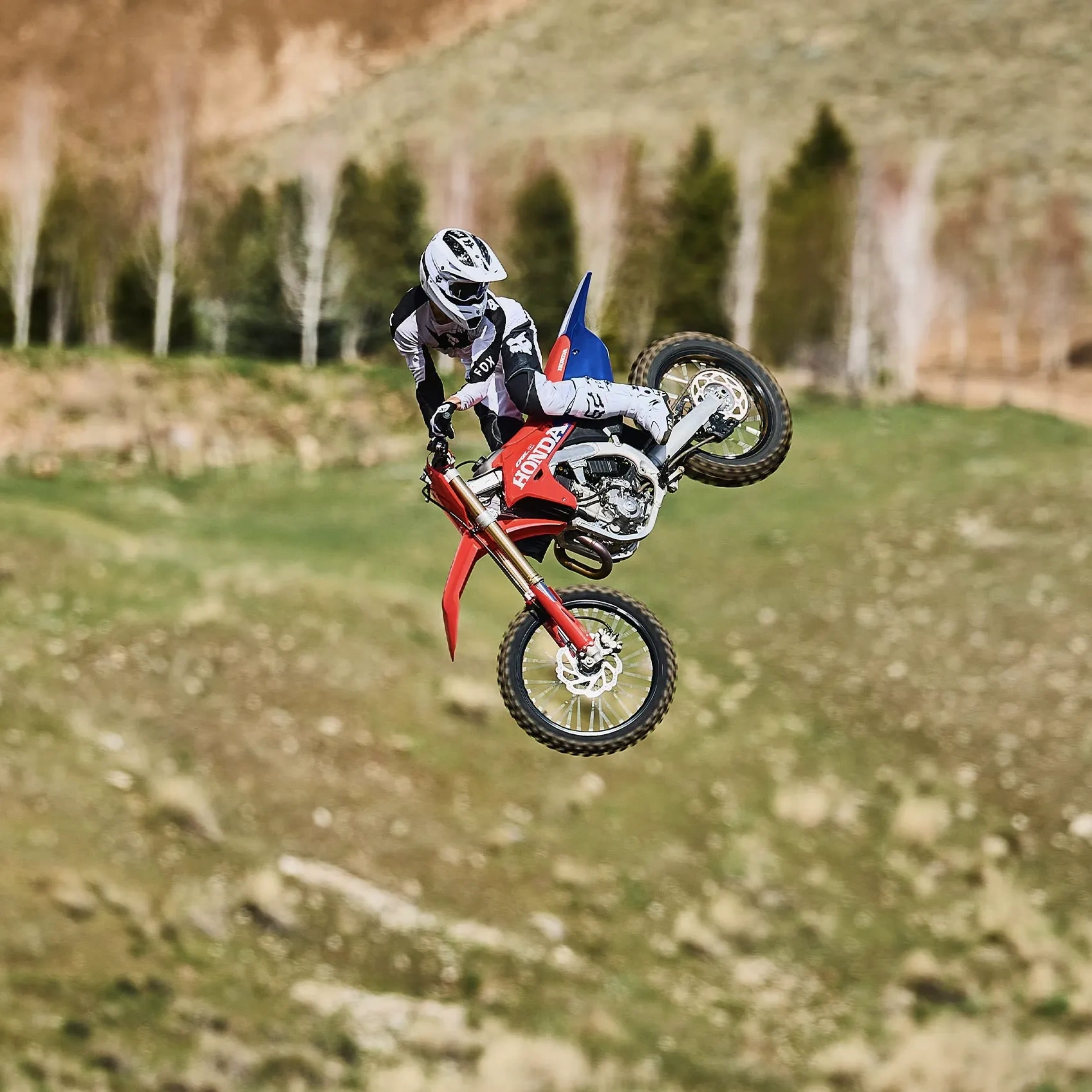 Honda CRF450R rouge en conduite sur un sentier boueux.