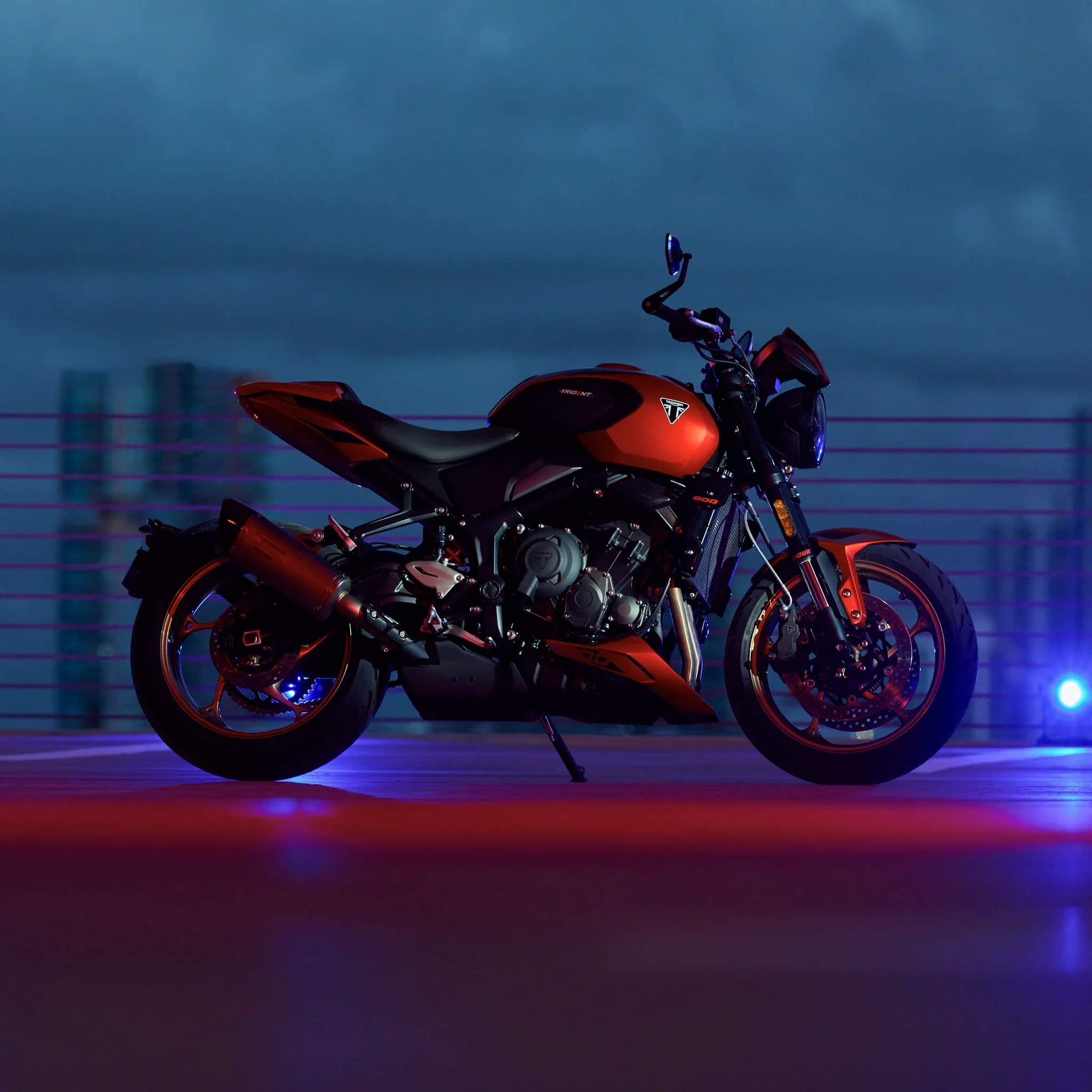 Triumph Trident 800 rouge garée de nuit en ville.