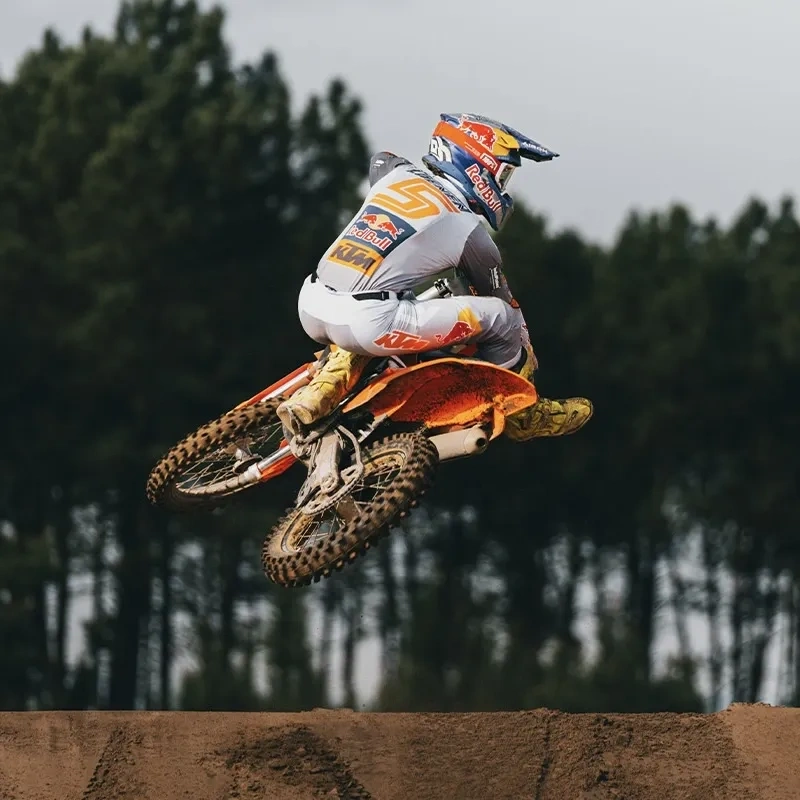 KTM 125 SX orange en saut sur un circuit de motocross.