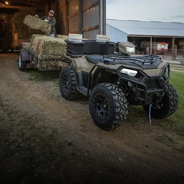 Polaris Sportsman 570 tirant une remorque chargée de balles de foin.