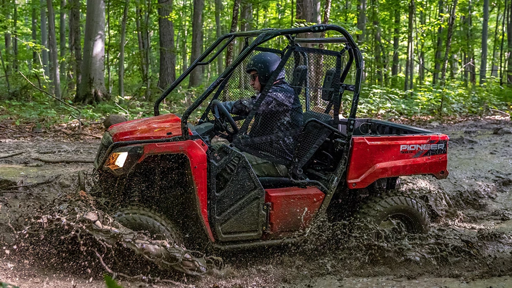 Vue d'un homme sur un VTT Honda Pioneer 520 2026 traversant une gigantesque boue
