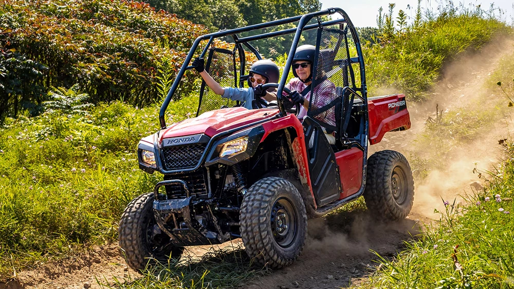 Vue d'une dame et son fils sur un Honda Pioneer 520 en puissance sur sentier escarpé