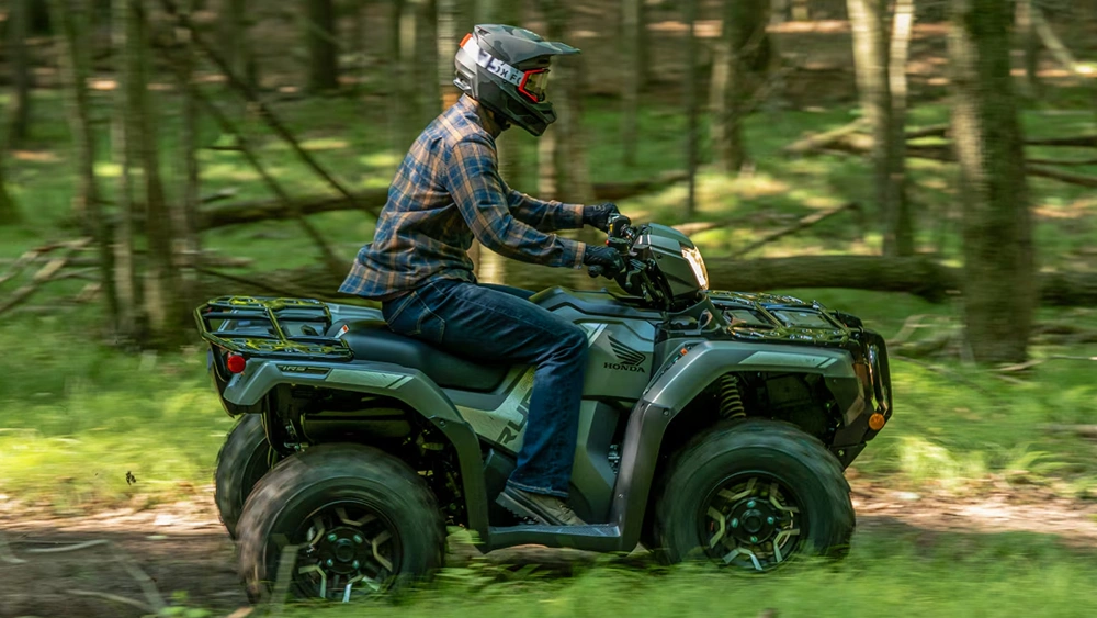 Homme sur VTT Honda Rubicon 2026 en pleine puissance en forêt