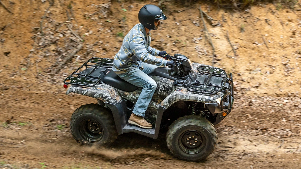Vue d'un chasseur sur VTT Honda Foreman 2026 sur chemin de terre en forêt