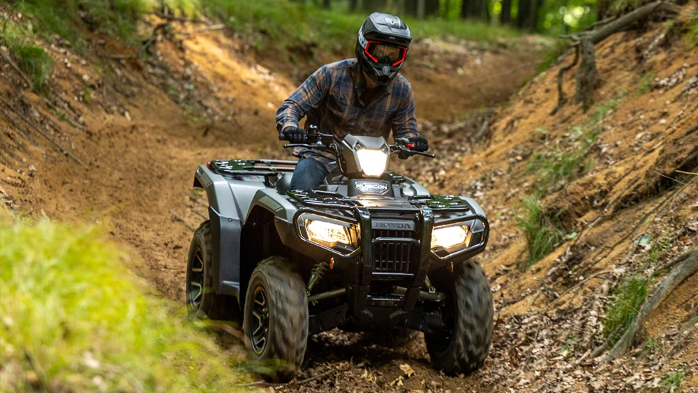 Vue d'un jeune homme sur VTT Honda Rubicon 2026 sur chemin escarpé