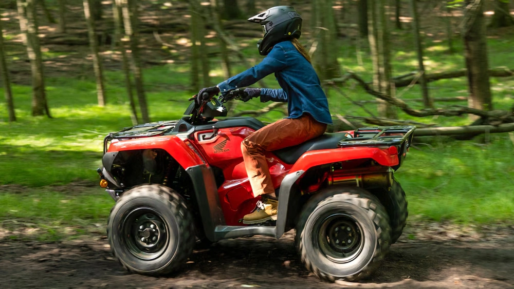 Vue d'une fille sur un Honda VTT Rancher 2026 sur chemin de boue