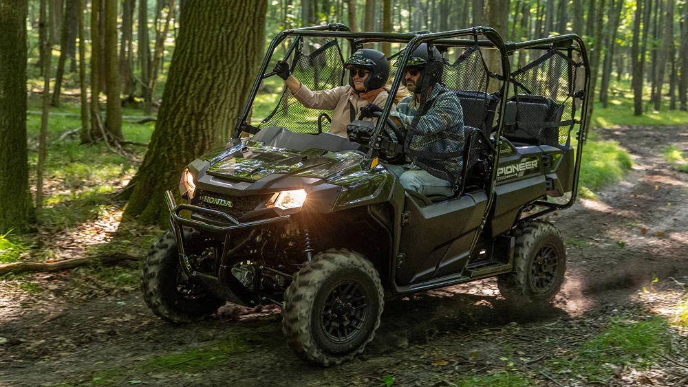 Vue latérale d'un couple sur un Honda Pioneer 700 en forêt 2026