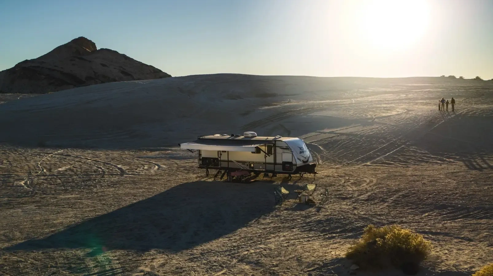Roulotte installée dans un paysage désertique au coucher du soleil, illustrant les nouvelles tendances de voyages en VR en 2026 axées sur la liberté et la nature.