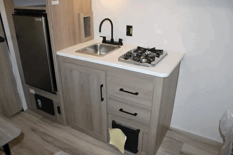 Cuisine compacte du Coleman 17R avec évier et cuisinière.