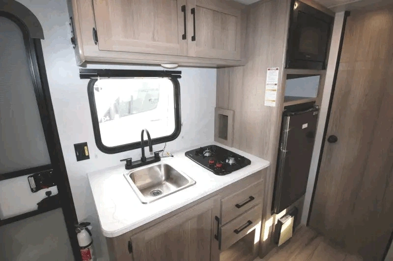 Cuisine du Coleman 17B avec évier, cuisinière et réfrigérateur.