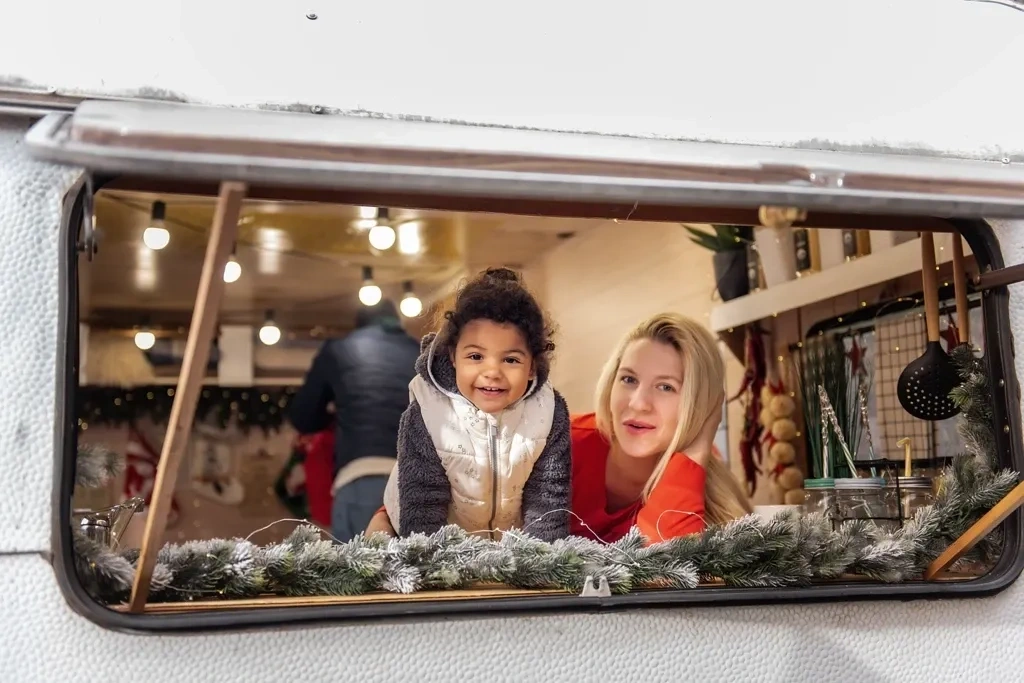 Famille profitant de l’intérieur chaleureux d’une roulotte décorée en hiver, mettant en valeur l’aspect convivial et pratique d’un achat de roulotte durant la saison froide.