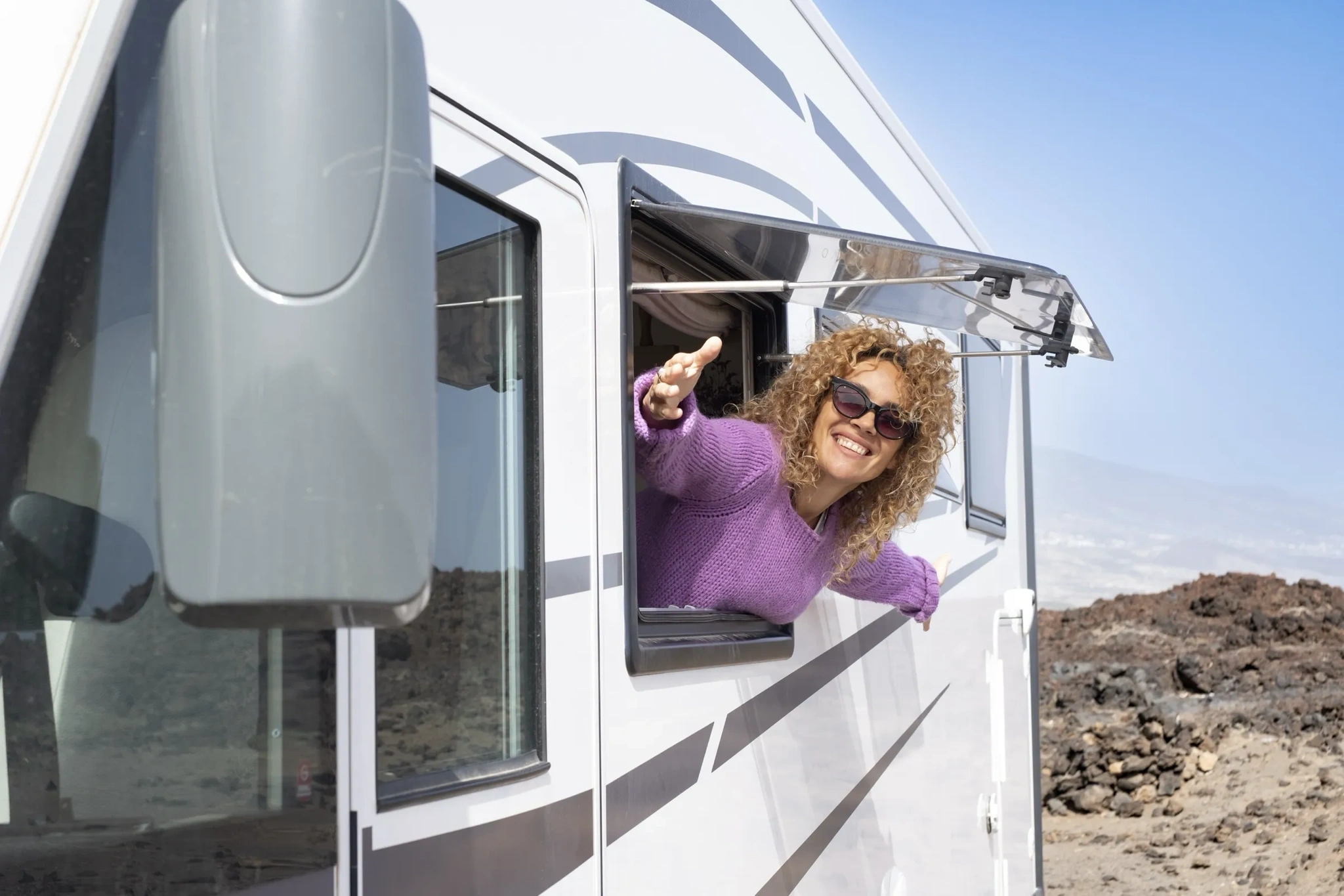 Une femme à la fenêtre de son VR, heureuse de partir en vacances.