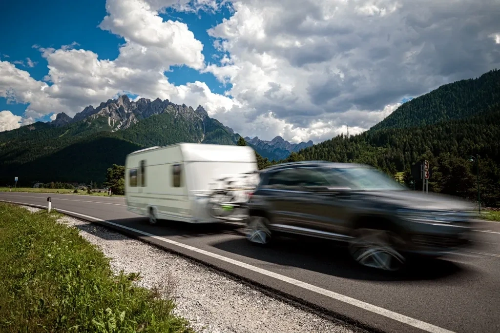 Véhicule remorquant une roulotte sur une route de montagne, illustrant l’importance du poids, du remorquage et de la compatibilité entre la roulotte et le véhicule.
