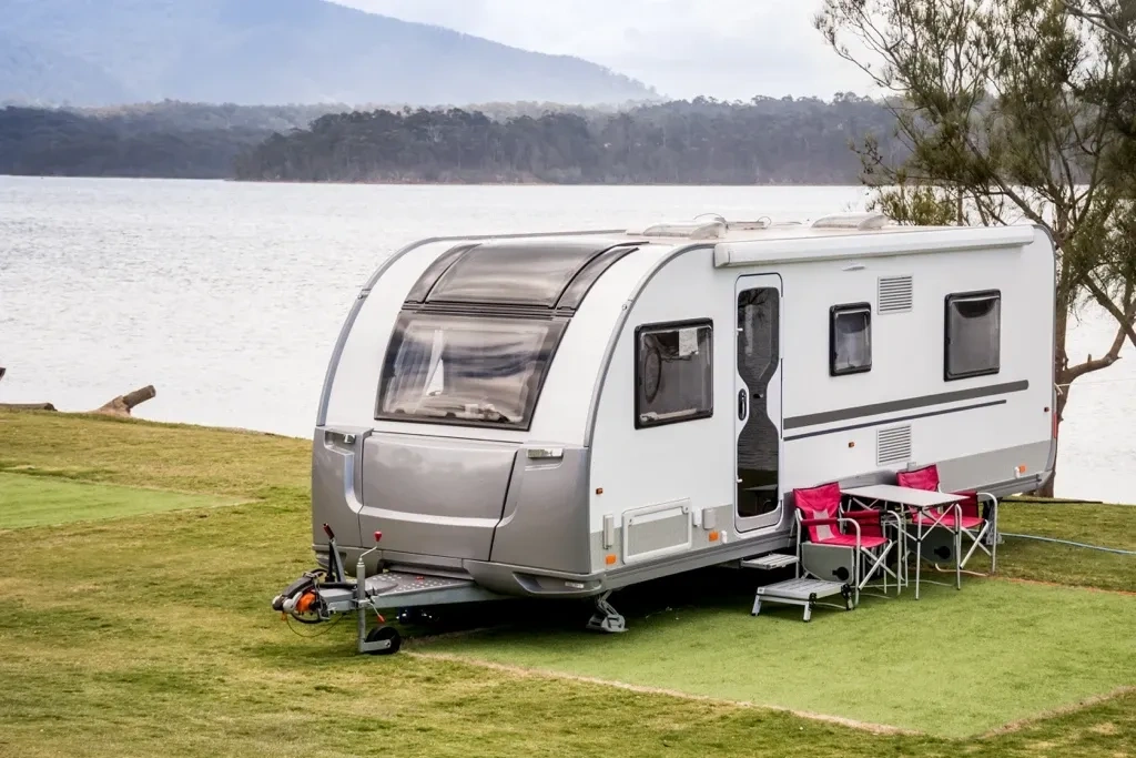 Roulotte moderne installée au bord d’un lac avec espace extérieur aménagé, illustrant le choix d’un modèle adapté au style de voyage, au confort et à l’environnement.