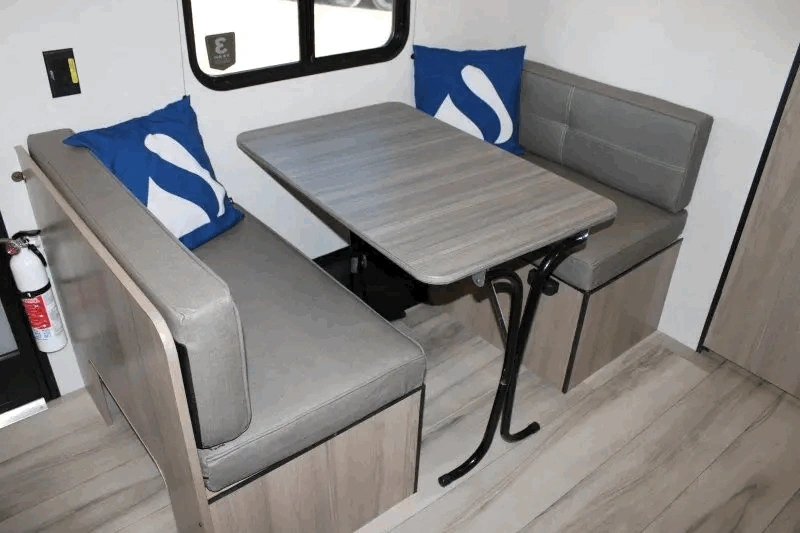 Dinette du Coleman 17R avec banquettes et table convertible.