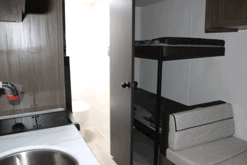 Intérieur du Prime Time Avenger LT 16BHX avec lits superposés et cuisine.