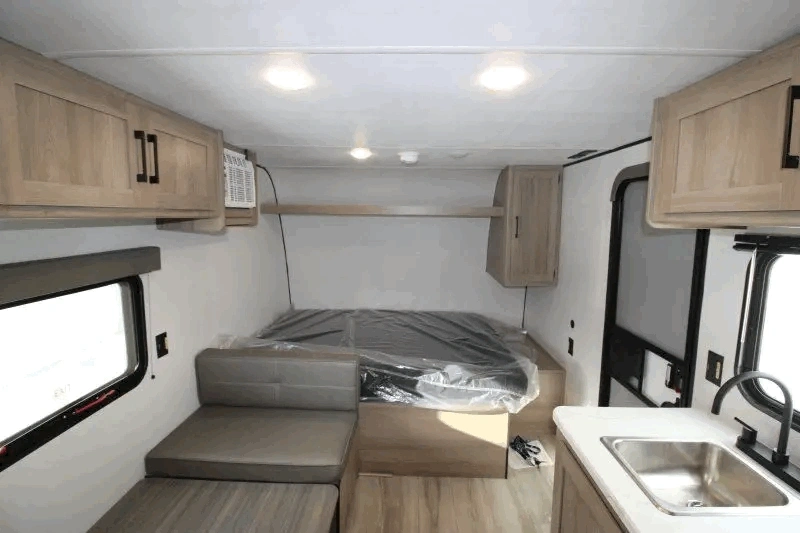 Lit avant et cuisine du Coleman 17B avec aménagement compact.