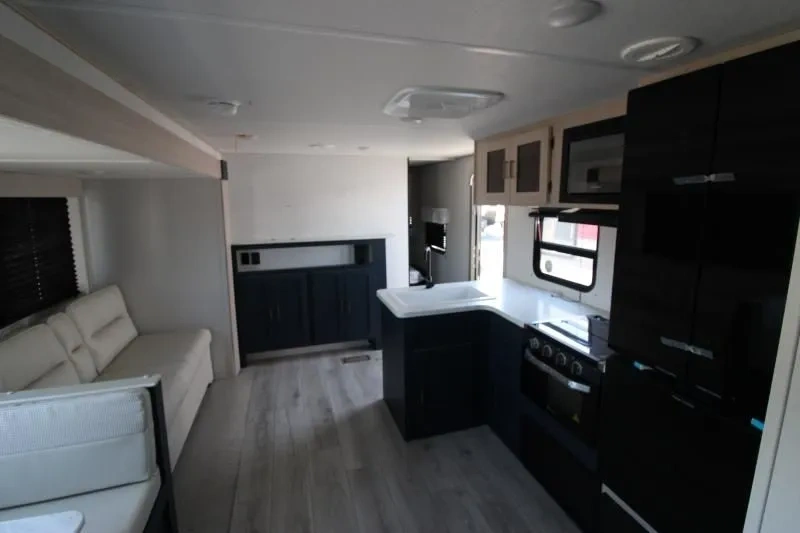 Vue de l’intérieur de l’Avenger 28QBS de Prime Time avec sofa, dinette familiale et cuisine en angle dans un style moderne épuré.