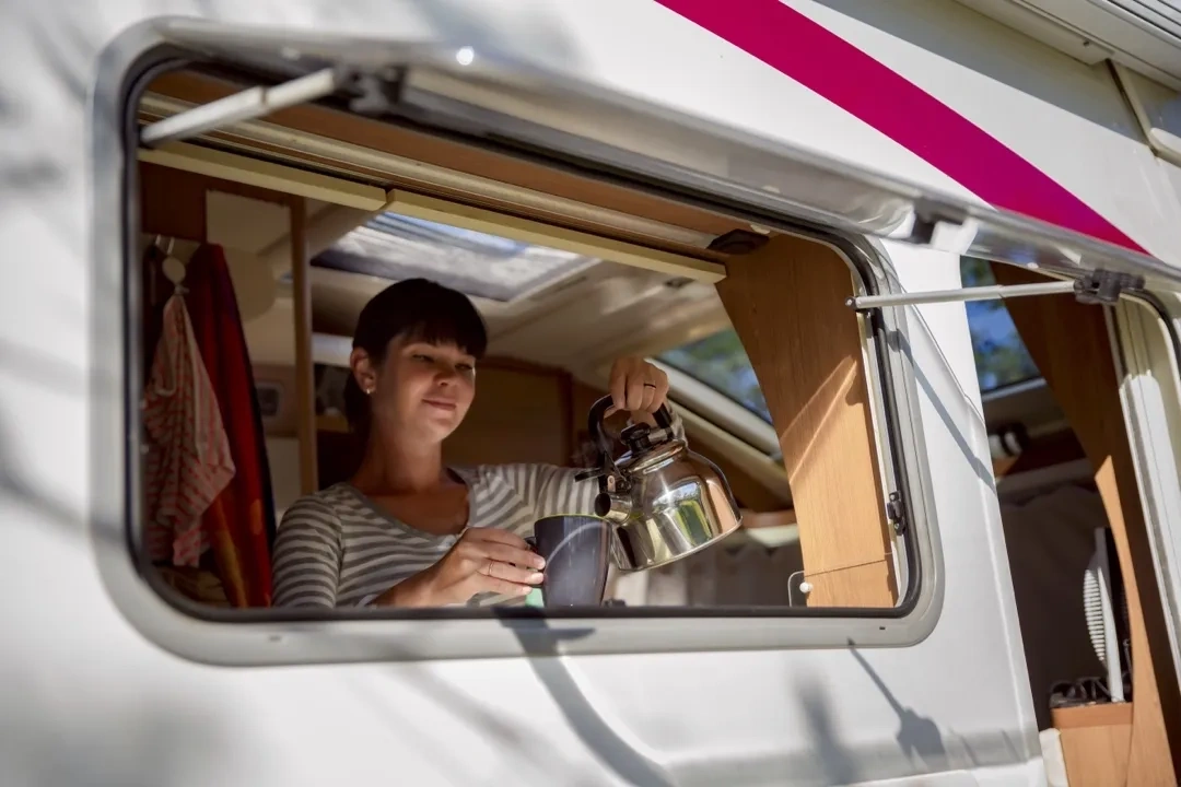 Un femme qui se sert un thé dans son véhicules récréatif.