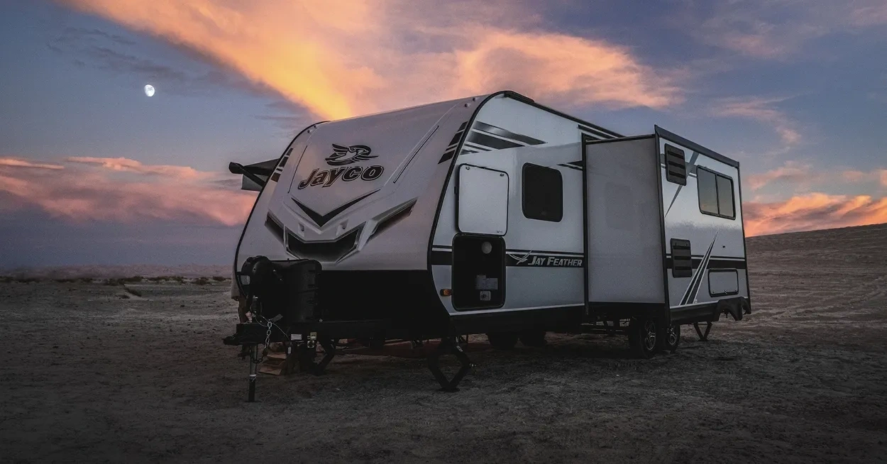 Roulotte stationnée au coucher du soleil, symbole d’un choix de matériaux durables et d’accessoires fiables pour le camping moderne.