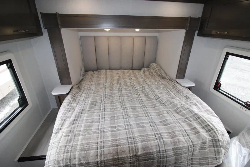 Lit arrière du Dynamax Isata 3 24RW avec couvre-lit à carreaux.
