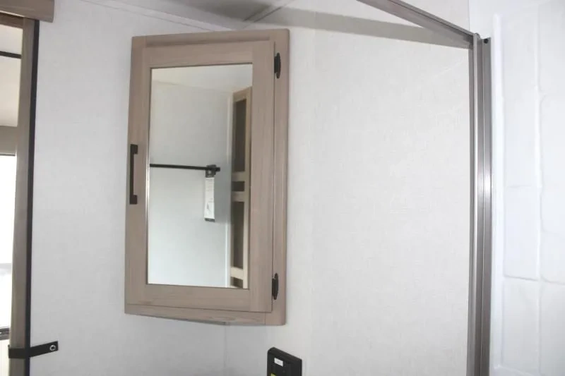Salle de bain de la Coleman Lantern 25REX avec miroir et porte de douche.