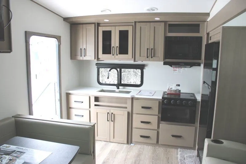 Cuisine arrière du Grand Design Reflection 100 Series 22RK avec armoires et cuisinière.