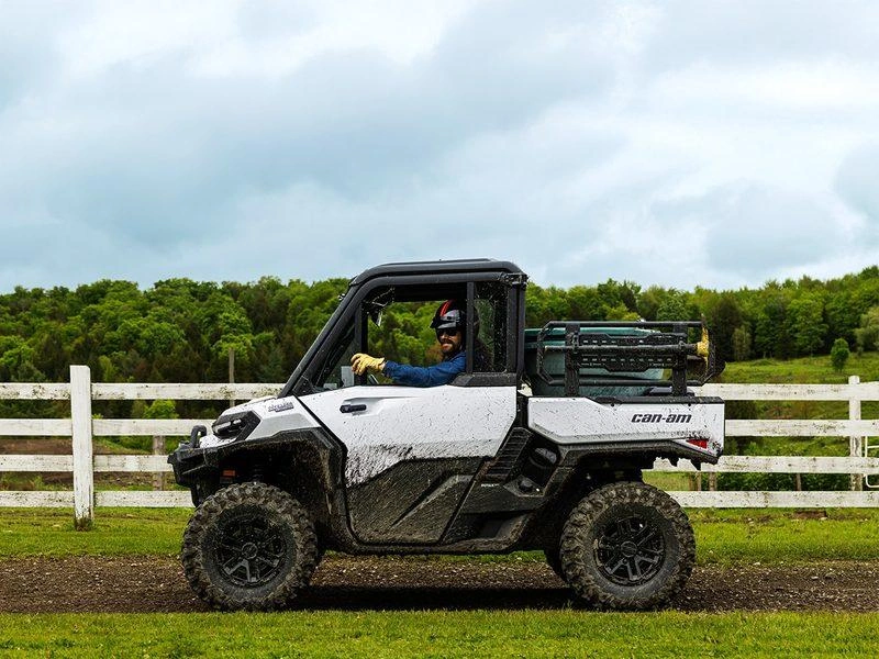 Can-Am Defender with a cab driving past a farm fence