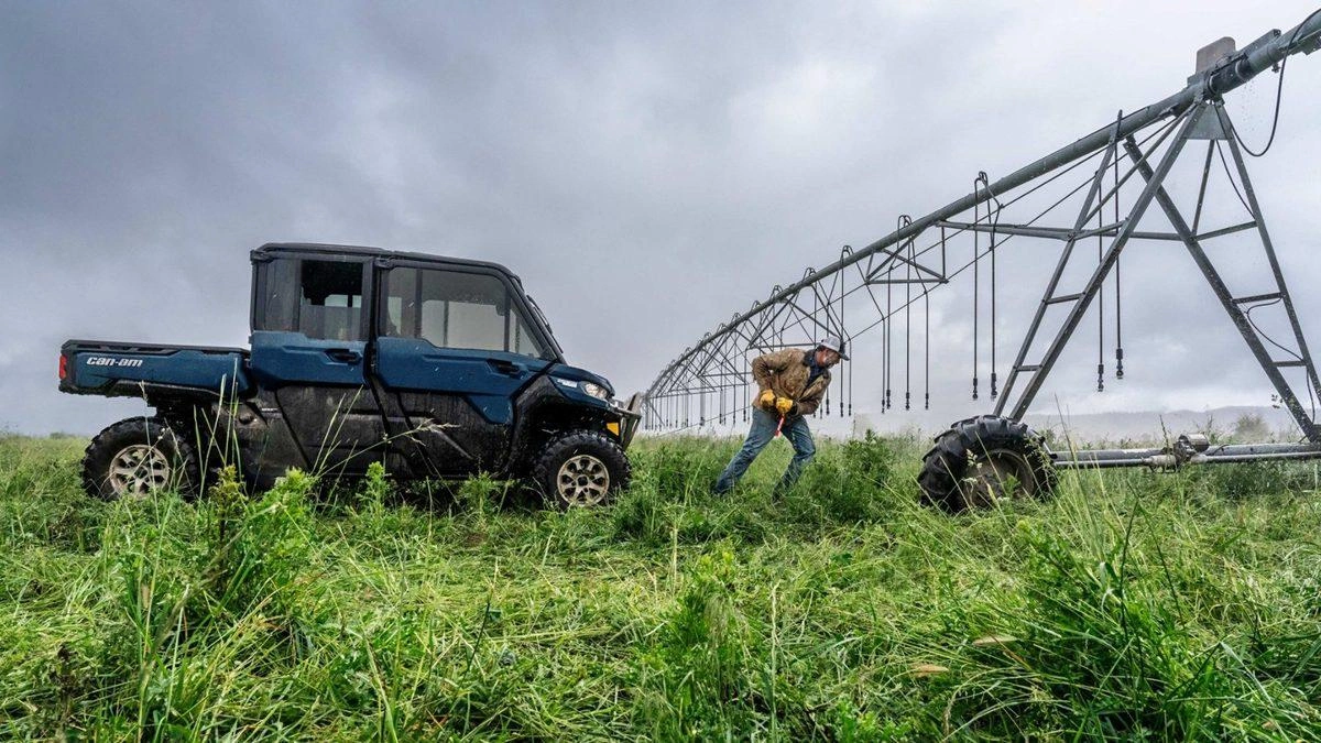 Can-Am Defender MAX Limited parked beside a centre-pivot irrigation system while a farmer works