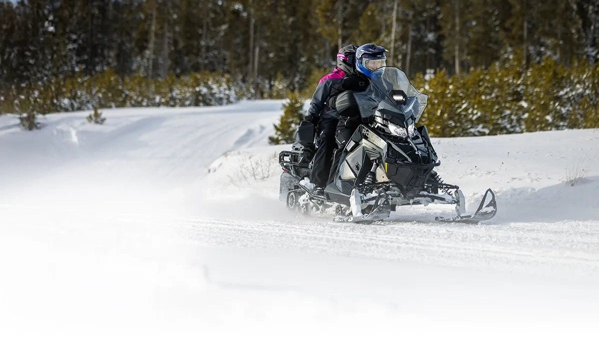 Randonnée à deux en Polaris Voyageur Adventure 2027 sur un sentier enneigé.