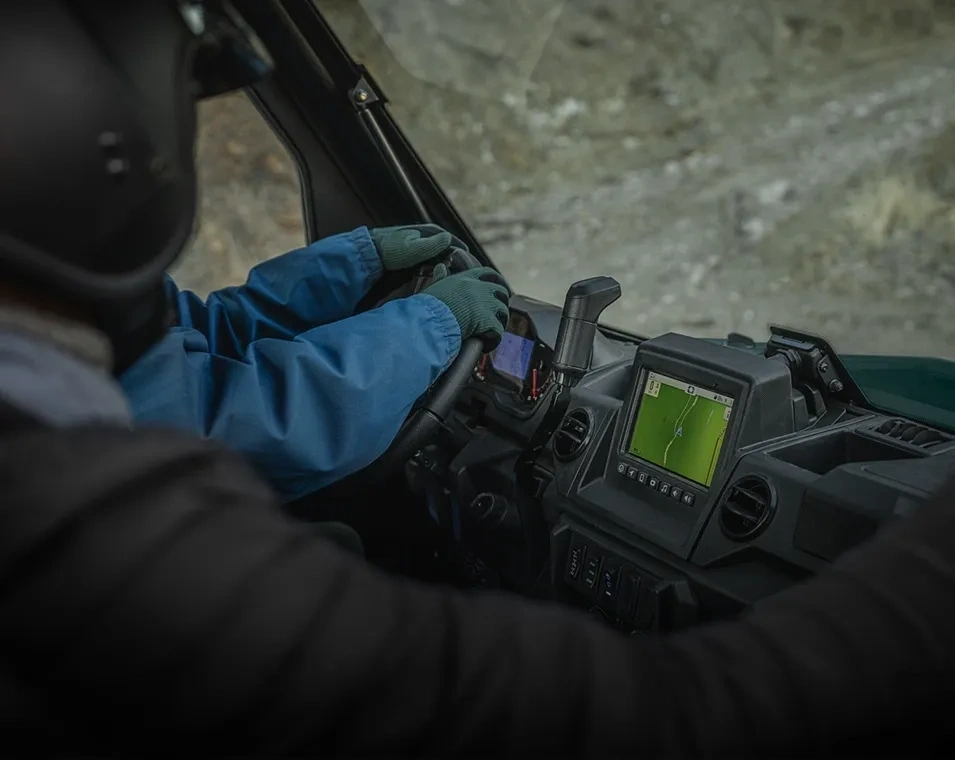 Intérieur du Polaris RANGER XP 1000 avec un conducteur ganté au volant et un écran au tableau de bord.