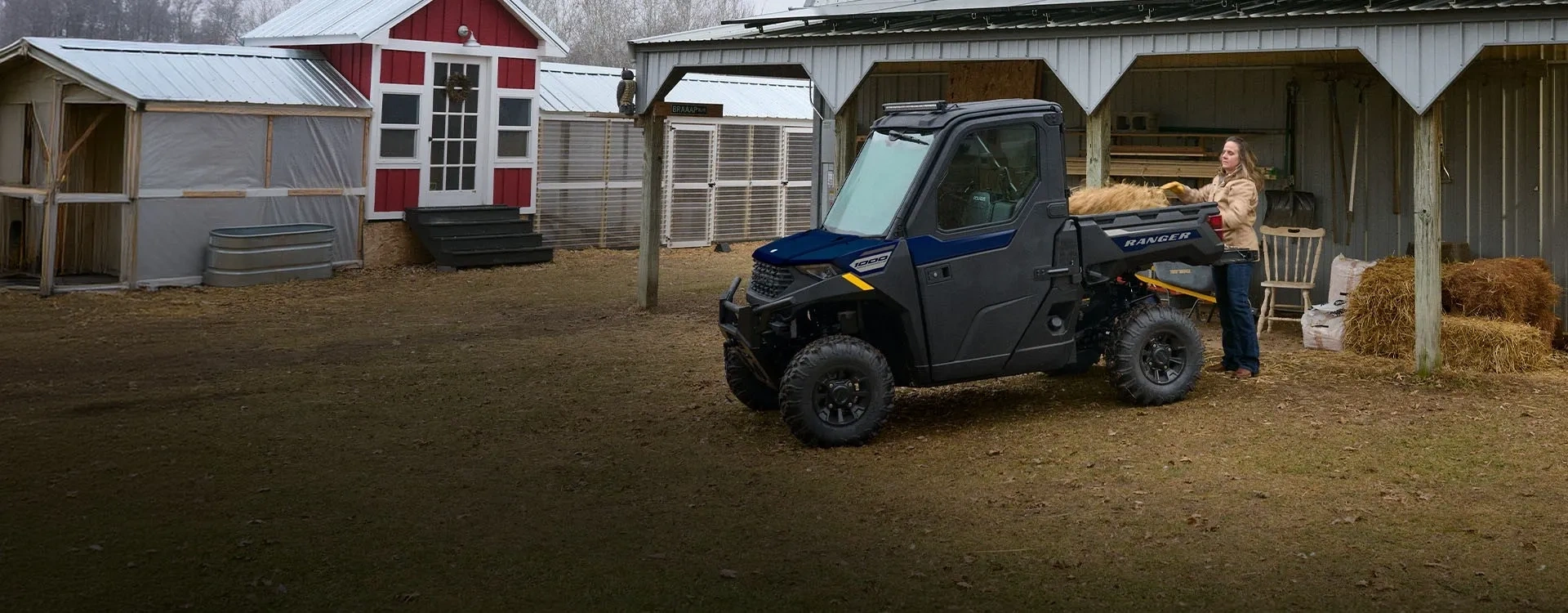 Polaris RANGER 1000 CAB 2027 bleu avec du foin dans la benne devant un bâtiment agricole.