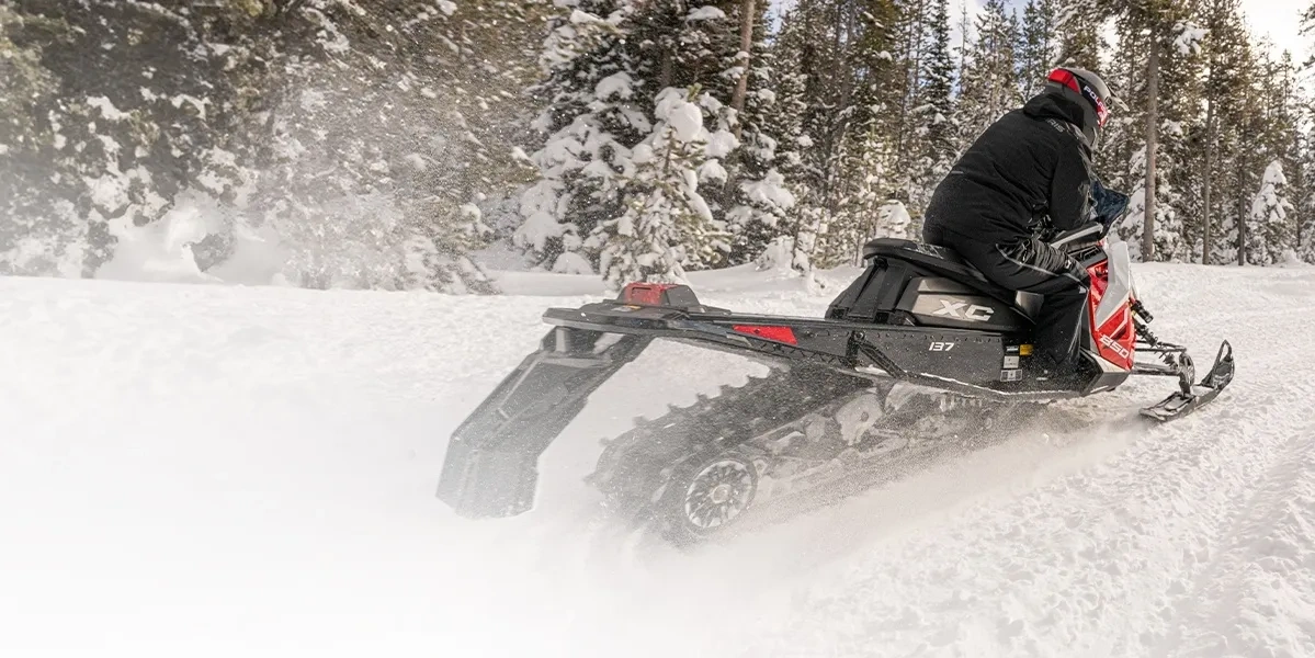 Polaris INDY XC 137 850 2027 vue de trois quarts arrière sur un sentier forestier enneigé.