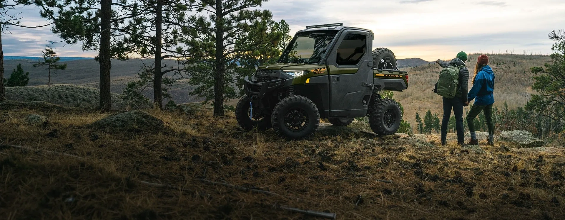 Polaris RANGER XP 1000 CAB 2027 stationné en montagne près de deux randonneurs.