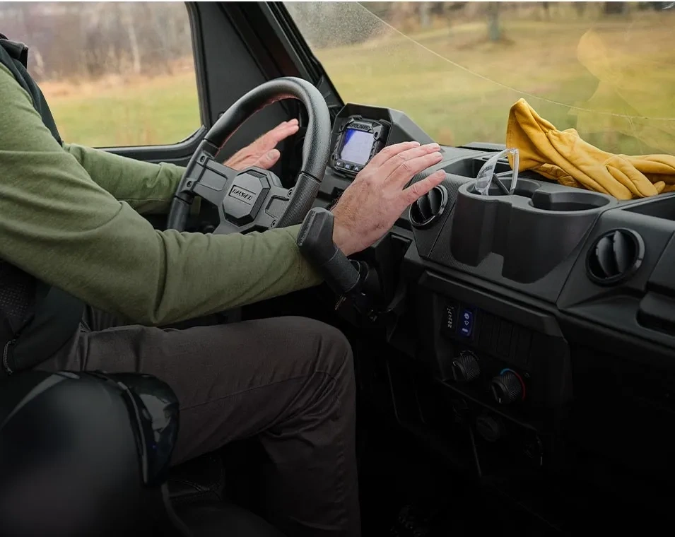 Vue du poste de conduite du Polaris RANGER 1000 avec le volant, le tableau de bord et les rangements.