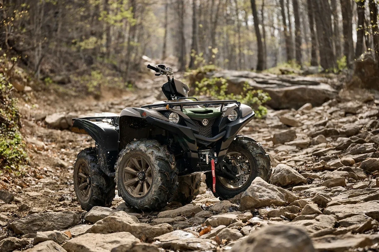 VTT Yamaha Grizzly EPS XT-R 2027 stationné sur un sentier rocheux en forêt.