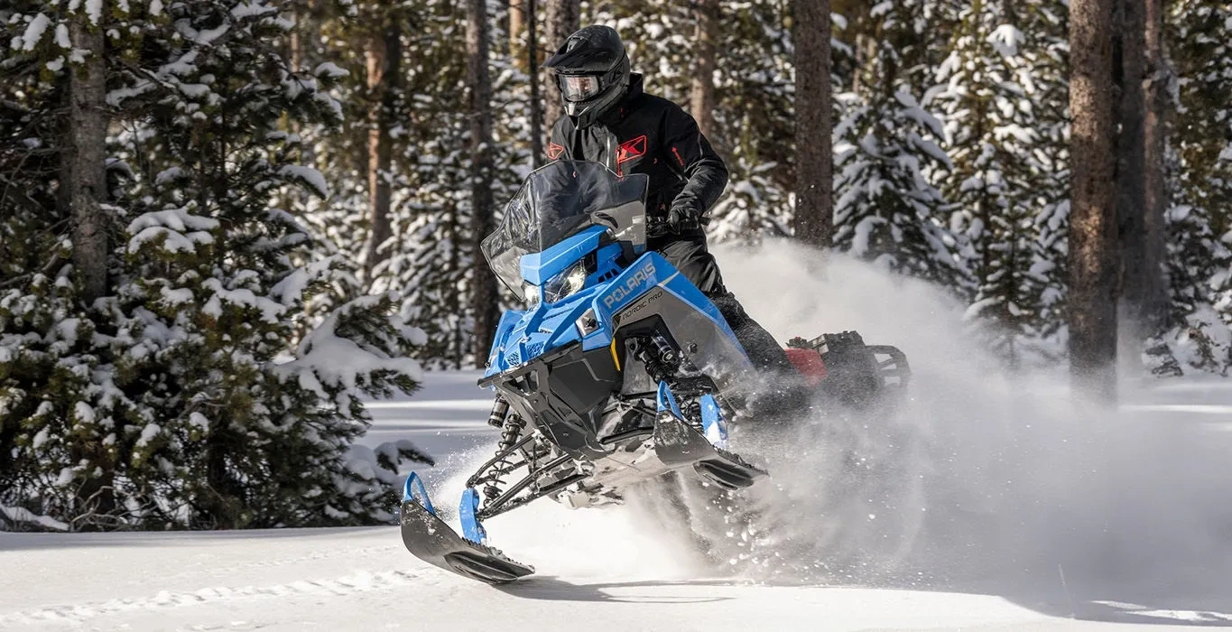 Polaris Voyageur équipée du moteur 650 Patriot en action dans la poudreuse en forêt.
