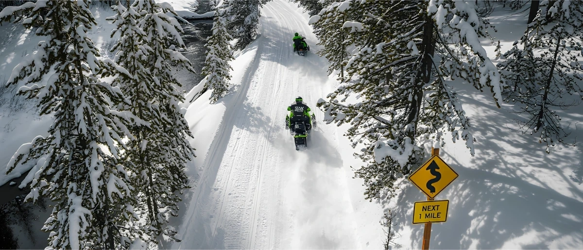 Snowmobilers on a snowy forest trail, illustrating the 2027 Arctic Cat snowmobile lineup.