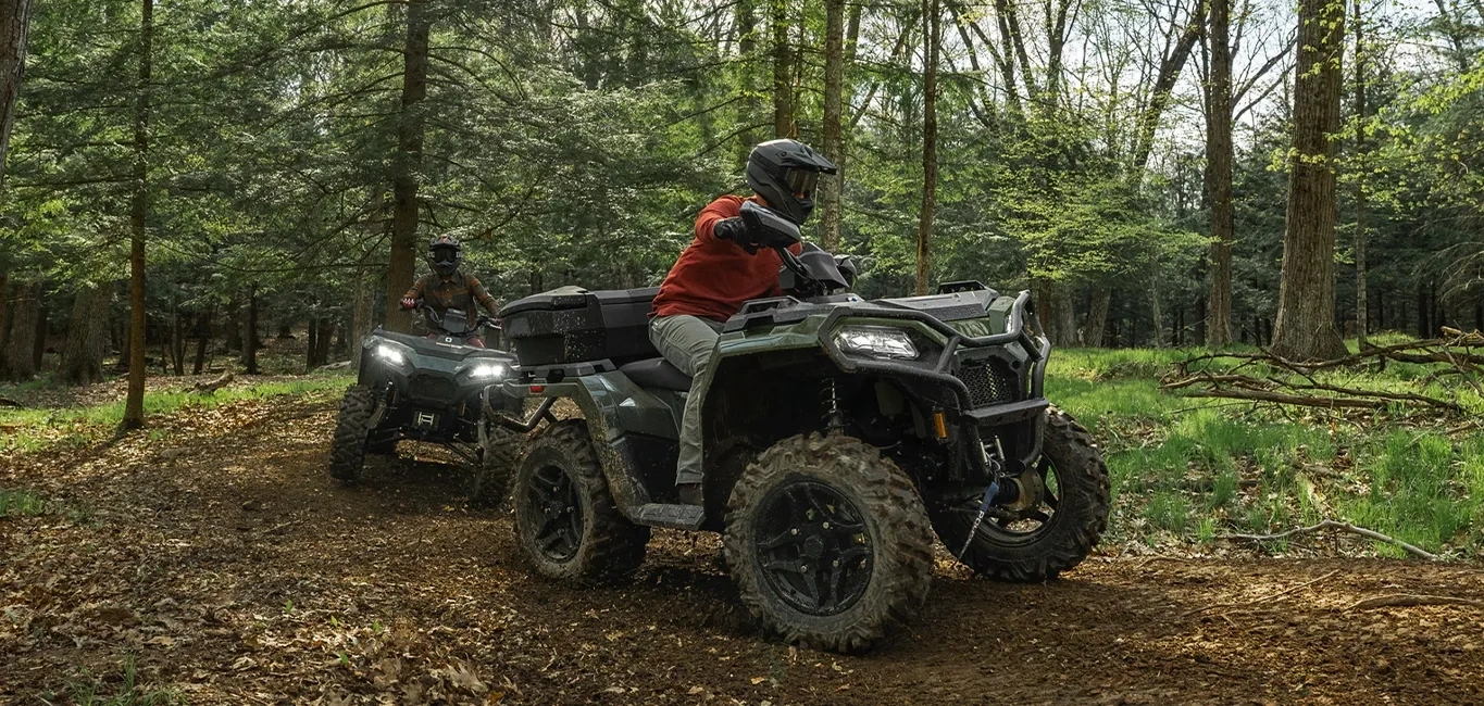 Polaris Sportsman 500 EPS 2027 avec son conducteur en randonnée sur un sentier forestier.